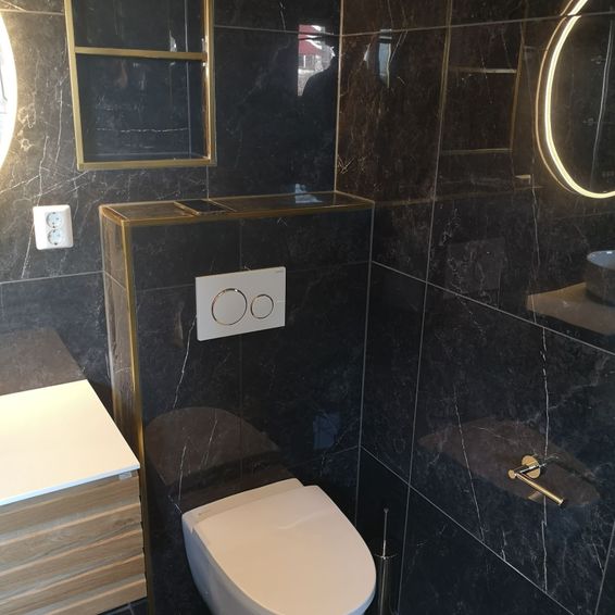 Vegghengt toalett på moderne bad med mørke fliser